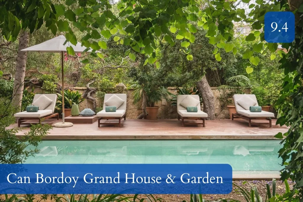 Tranquil garden pool surrounded by lush greenery, mature trees, wooden decking, and luxury sun loungers at Can Bordoy Grand House & Garden in La Lonja, Palma de Mallorca