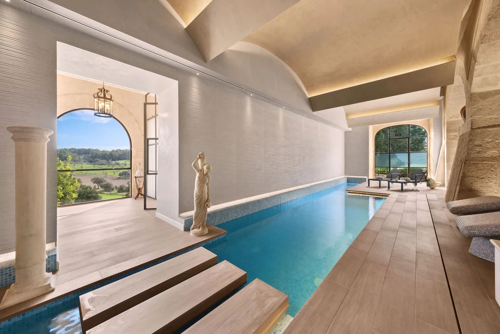 Elegant indoor spa pool with floor-to-ceiling arched windows at Finca Sa Bastida Luxury Retreat & Spa in Sant Joan, Mallorca.
