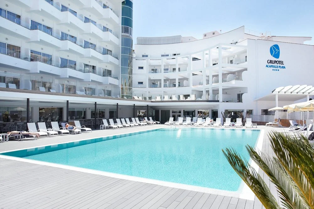 Grupotel Acapulco Playa in Playa de Palma with a large outdoor swimming pool, sun loungers, and modern hotel building.