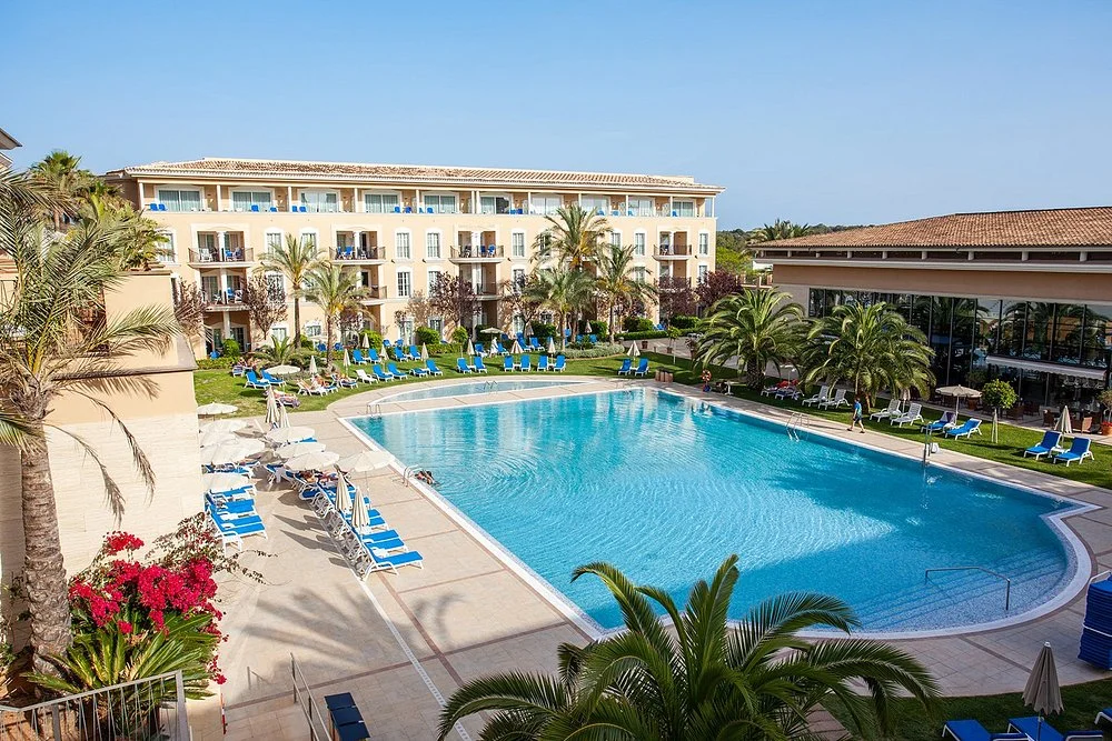 Grupotel Playa de Palma Suites & Spa in Playa de Palma with a large outdoor swimming pool, landscaped gardens, and hotel buildings.