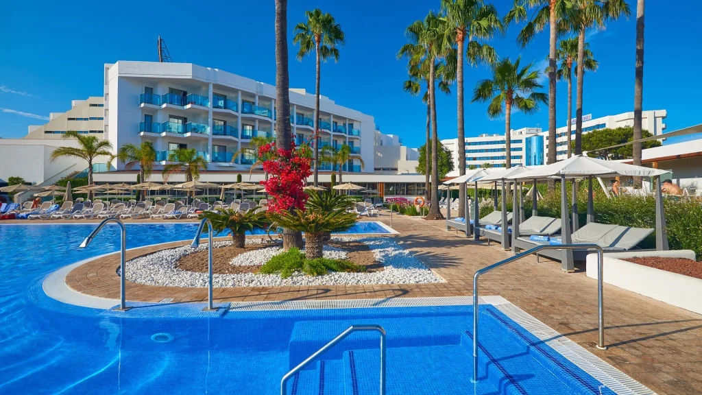Main pool with palm trees and hotel building at Hipotels Cala Millor Park in Cala Millor, Mallorca.