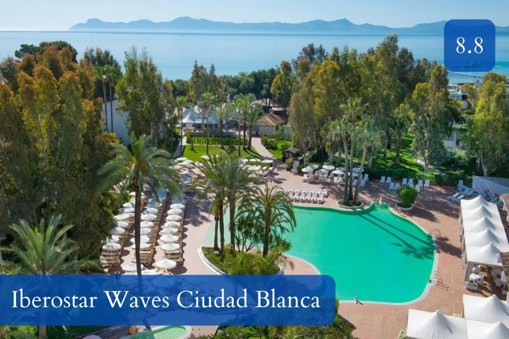 Swimming pool and garden area with views of Alcúdia Bay at Iberostar Waves Ciudad Blanca, Mallorca.