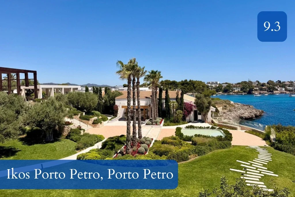 Landscaped gardens with palm trees and coastal views at Ikos Porto Petro in Porto Petro, Mallorca