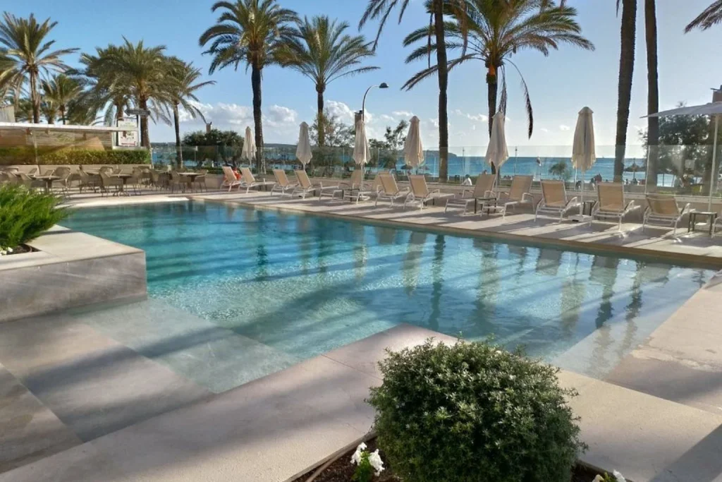Beachfront outdoor swimming pool with sun loungers and Mediterranean Sea views at MySeaHouse Flamingo in Playa de Palma, Mallorca.