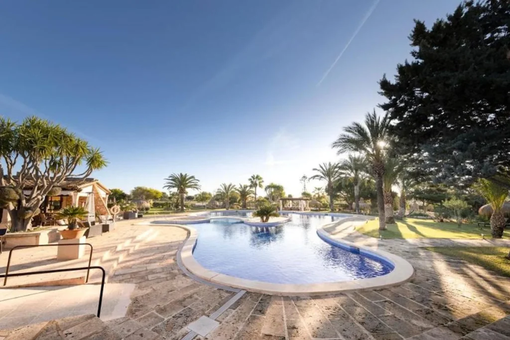 Outdoor pool surrounded by palm trees and gardens at Agroturismo Finca Sa Tanca in Campos, Mallorca.
