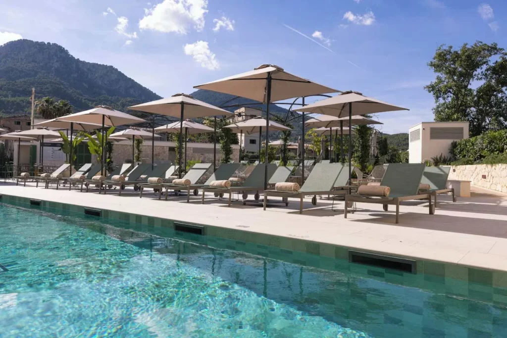 Modern outdoor swimming pool with sun loungers, parasols, and mountain views at Alcázar Hotel Sóller in Sóller, Mallorca.