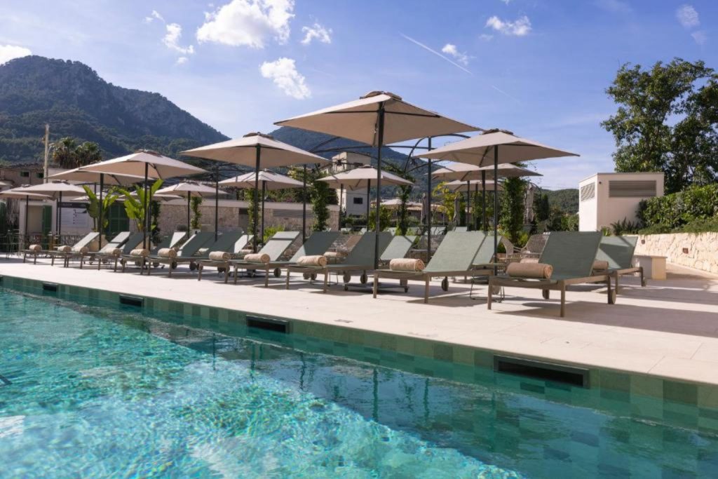 Outdoor swimming pool with sun loungers, parasols, and mountain views at Alcázar Hotel Sóller in Sóller, Mallorca