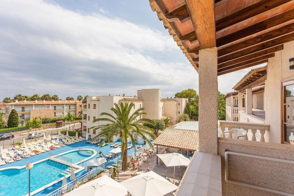 Elevated view of the outdoor swimming pool, sun terrace, and apartment balconies at Aparthotel Ferrer Isabel in Cala Bona, Mallorca.