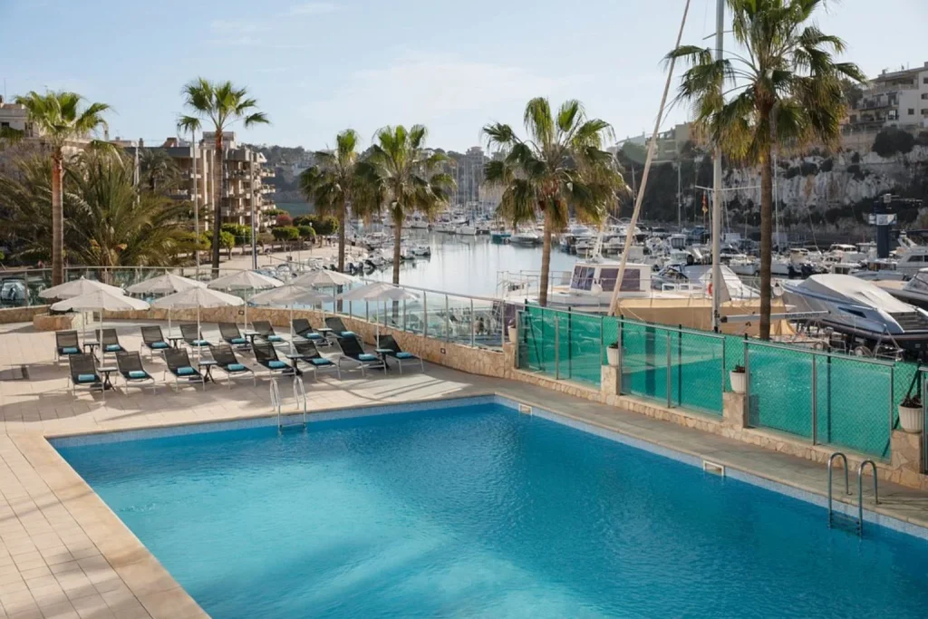 Outdoor swimming pool and marina view at Aparthotel Porto Drach in Porto Cristo, Mallorca