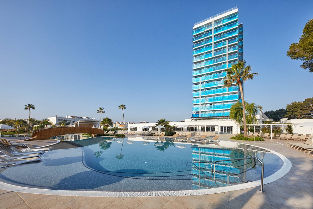 Outdoor swimming pool with tower hotel building at BG Tonga Tower Design Hotel & Spa in Can Picafort, Mallorca.