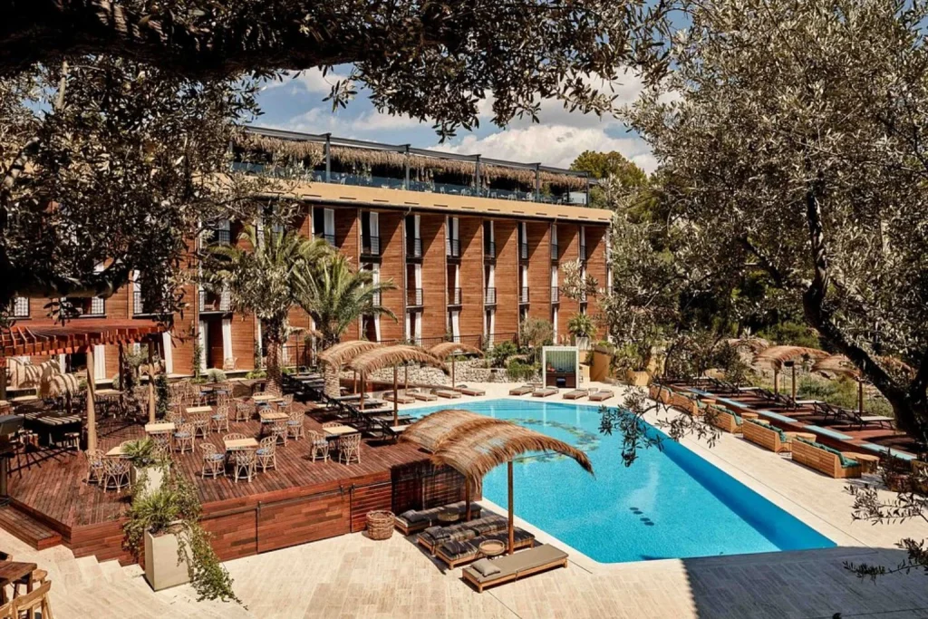 Outdoor swimming pool with daybeds, wooden sun deck, and tropical lounge area at Bikini Island & Mountain Hotel Port de Sóller in Port de Sóller, Mallorca
