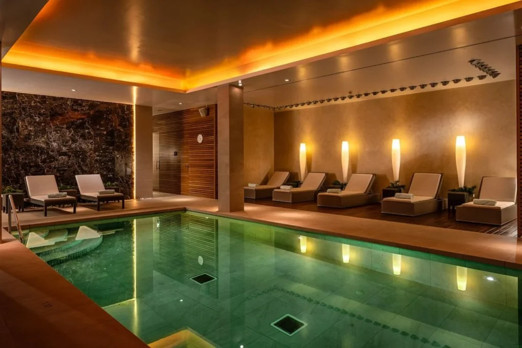Indoor spa pool with relaxation loungers and ambient lighting at Bellesa de Claret Spa in Castell Son Claret, Es Capdellà, Mallorca.