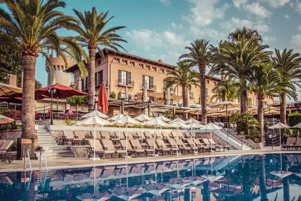 Main outdoor swimming pool surrounded by palm trees at Castillo Hotel Son Vida in Palma, Mallorca.