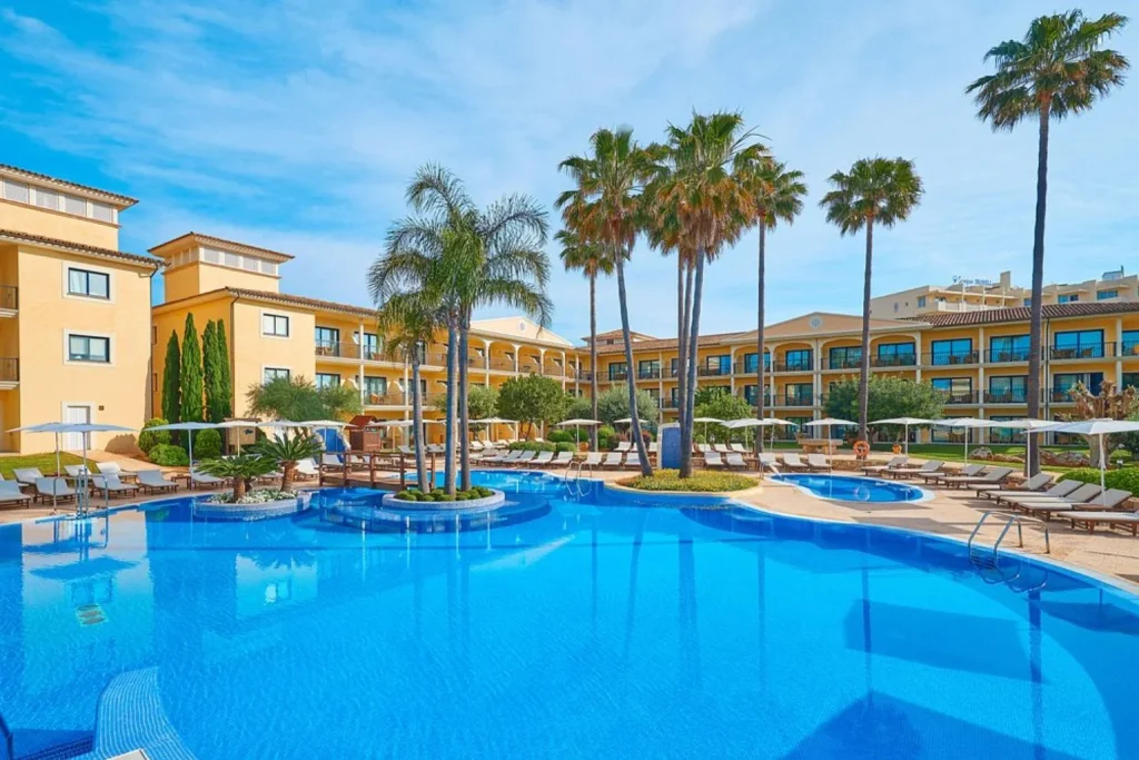 Lagoon-style outdoor pool with palm trees at CM Mallorca Palace in Sa Coma, Mallorca