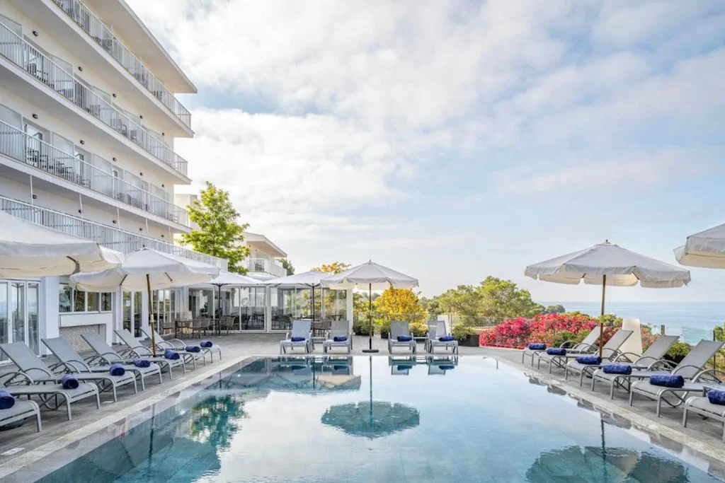 Outdoor pool with sun loungers overlooking the sea at Exe Portals Nous in Portals Nous, Mallorca.
