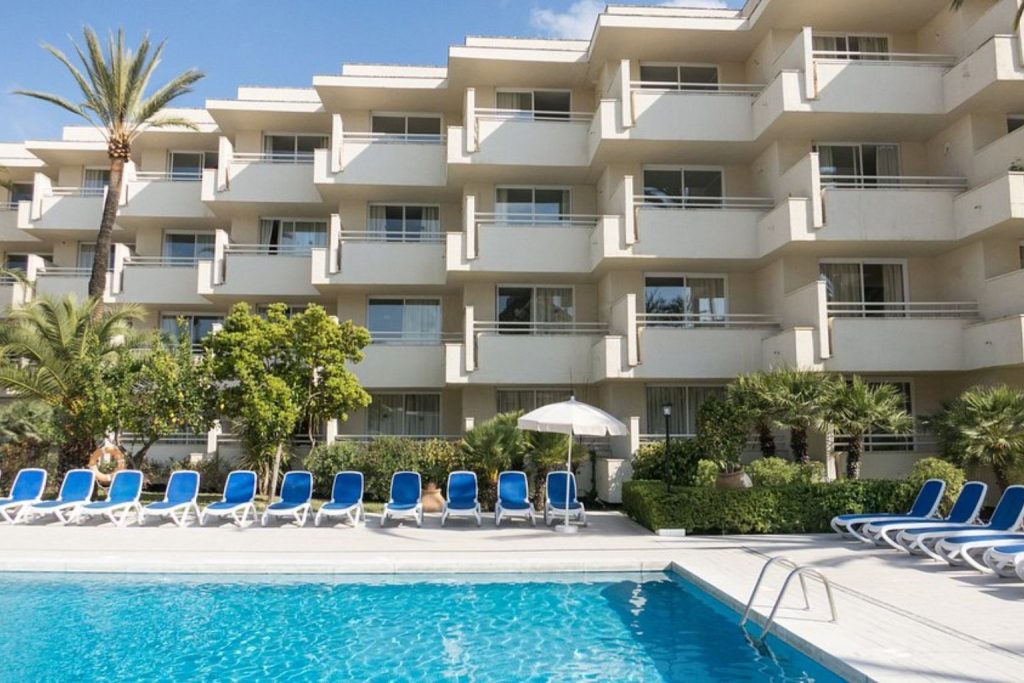 Outdoor swimming pool with sun loungers and hotel balconies at Globales Cala Bona in Cala Bona, Mallorca.