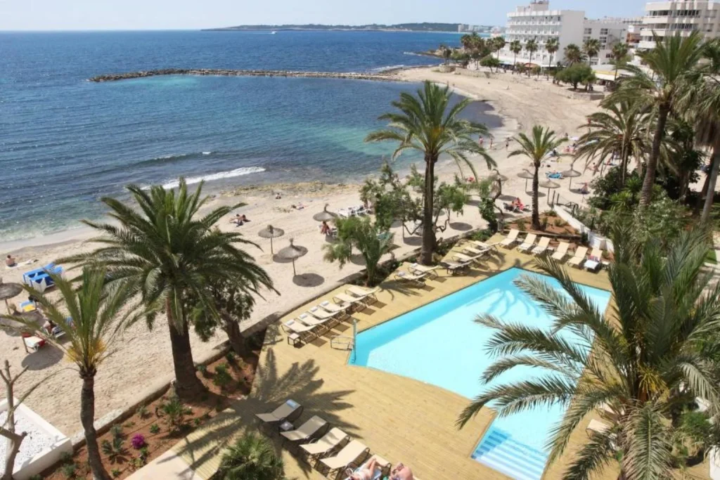 Beachfront swimming pool, sandy cove, and Mediterranean coastline at Gran Sol Hotel in Cala Bona, Mallorca.