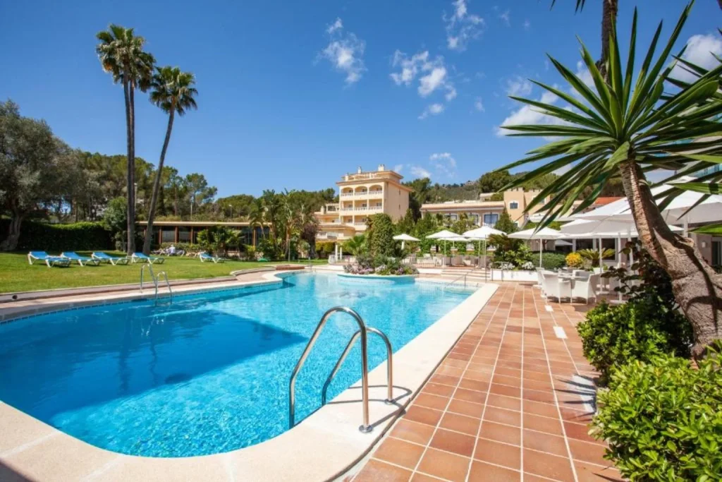 Large outdoor swimming pool surrounded by gardens at Grupotel Nilo & Spa in Peguera, Majorca.