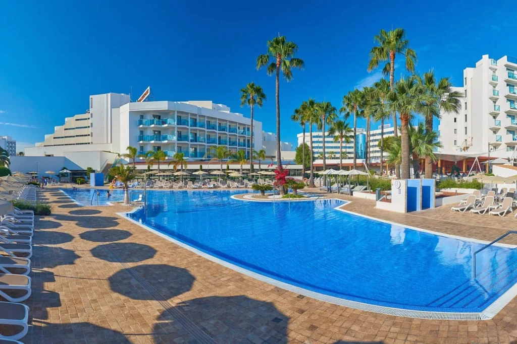 Large outdoor swimming pool surrounded by palm trees at Hipotels Cala Millor Park in Cala Millor, Majorca.