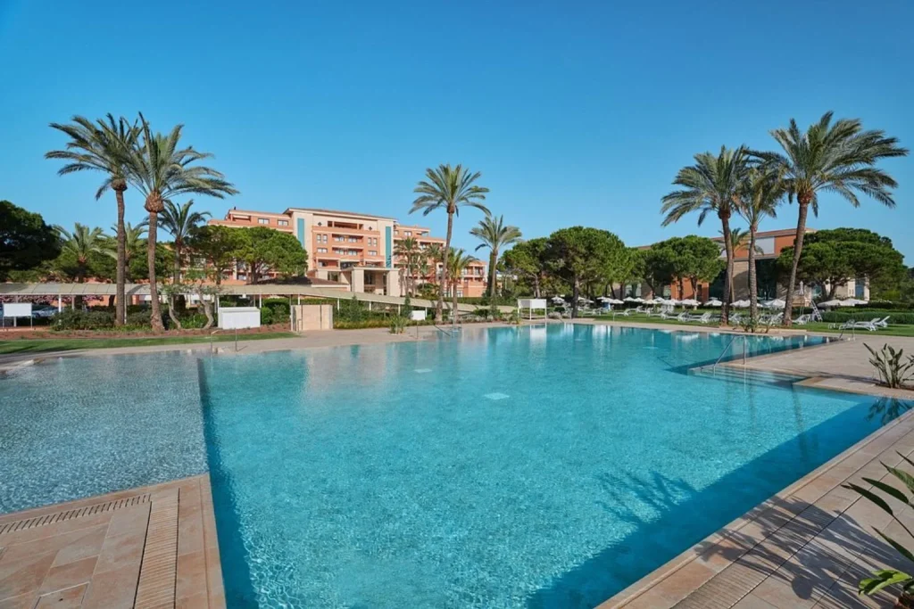 Main outdoor swimming pool surrounded by palm trees and landscaped gardens at Hipotels Hipocampo Palace & Spa in Cala Millor, Mallorca.