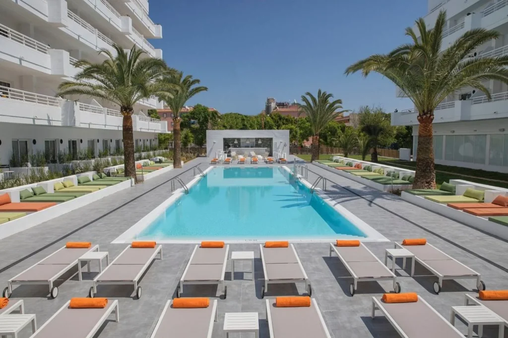 Main outdoor swimming pool with sun loungers and palm trees at HM Martinique in Magaluf, Mallorca.