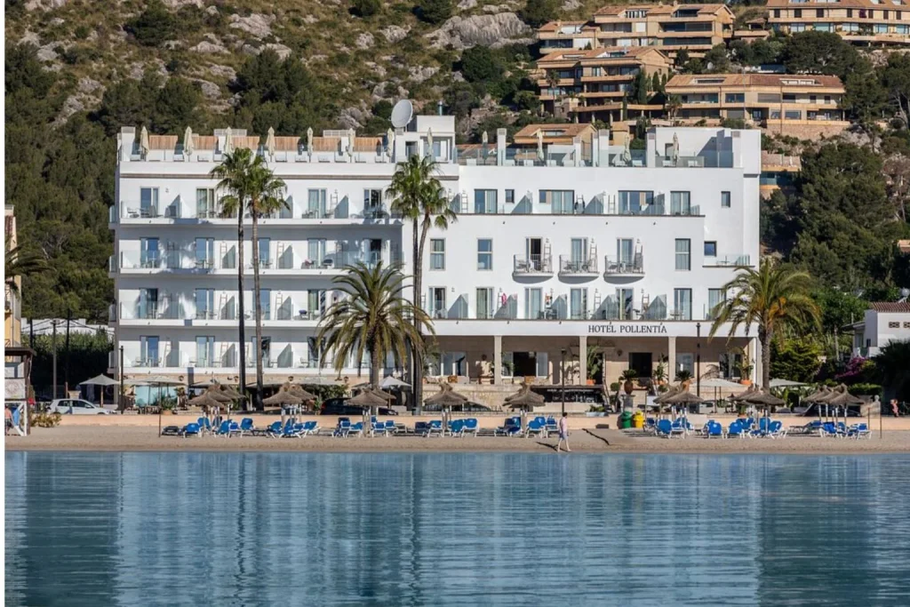 Beachfront hotel building with sandy beach and sun loungers at Hoposa Pollentia in Port de Pollença, Mallorca