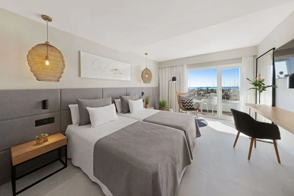 Modern guest room with twin beds, a private balcony, and city views at Hotel Almudaina in Palma de Mallorca.
