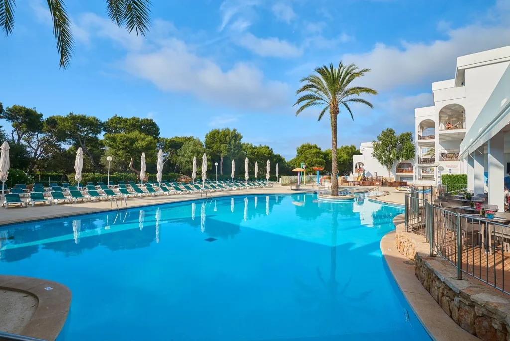 Outdoor swimming pool with palm trees at Hotel Cala d'Or Playa in Cala d'Or, Mallorca.