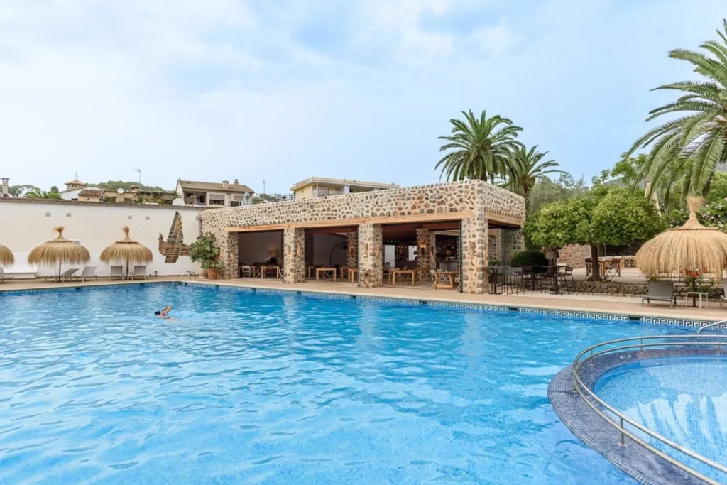 Outdoor swimming pool with a stone pool bar, hot tub, and sun terrace at Hotel Es Port in Port de Sóller, Mallorca
