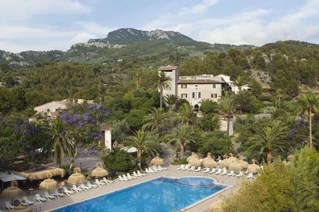 Outdoor pool set among lush gardens with views of the Tramuntana Mountains at Hotel Es Port in Sóller.