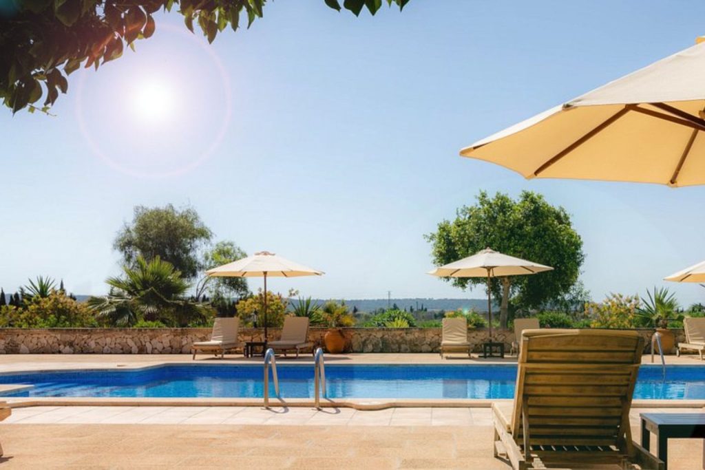 Outdoor swimming pool with sun loungers, parasols, and countryside views at Hotel Migjorn Mallorca in Campos, Mallorca