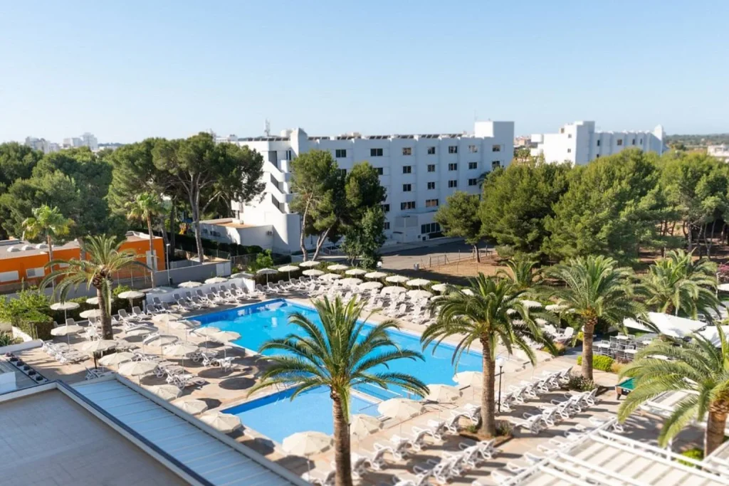 Outdoor swimming pool surrounded by palm trees at Hotel Millor Sol in Cala Millor, Majorca.