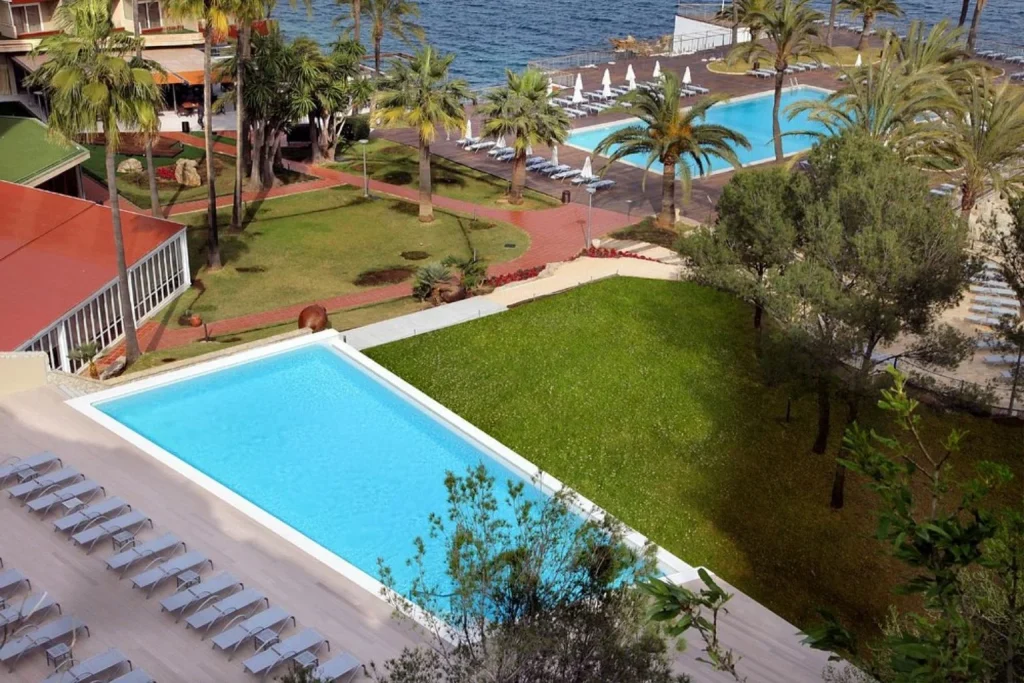 Seafront swimming pools with sun loungers and views of the Mediterranean coastline at Hotel Palace Bonanza Playa & Spa in Illetas, Mallorca