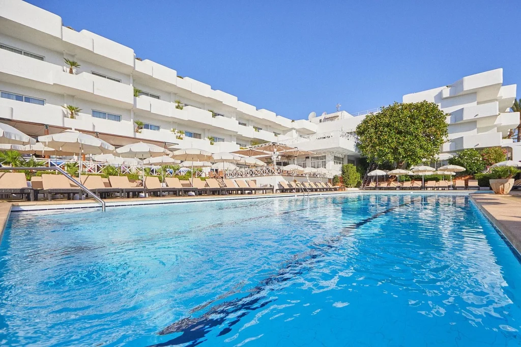 Outdoor swimming pool with sun loungers and hotel building at Hotel Rocamarina – Adults Only in Cala d'Or, Mallorca.