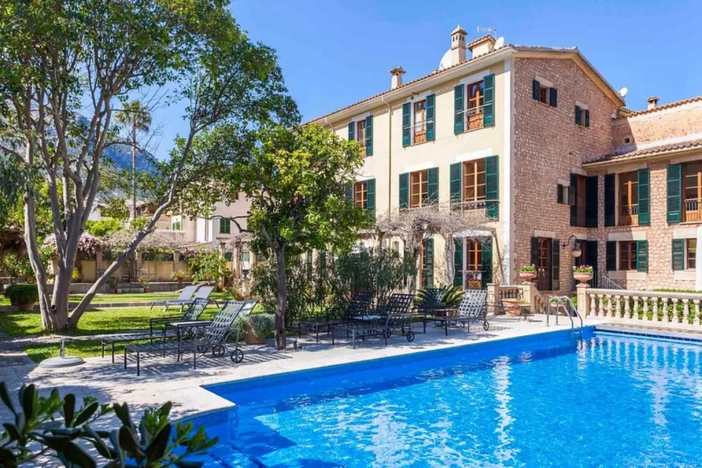 Outdoor swimming pool surrounded by gardens and a restored stone manor house at Hotel Salvia in Sóller, Mallorca.