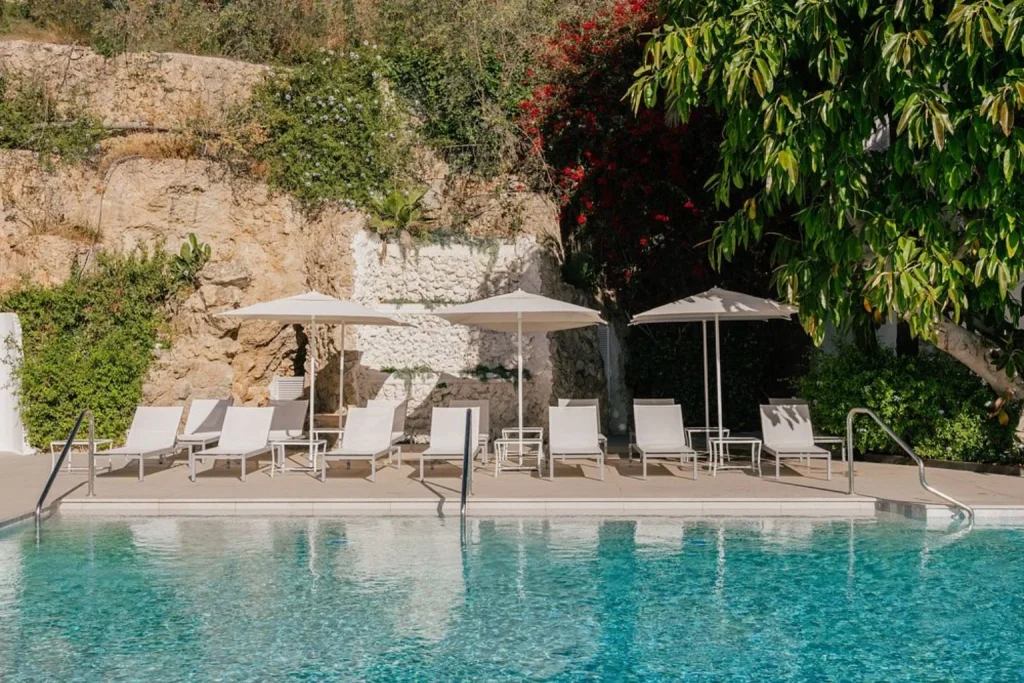Outdoor swimming pool with sun loungers and umbrellas at Hotel Victoria Gran Meliá in Palma Bay.