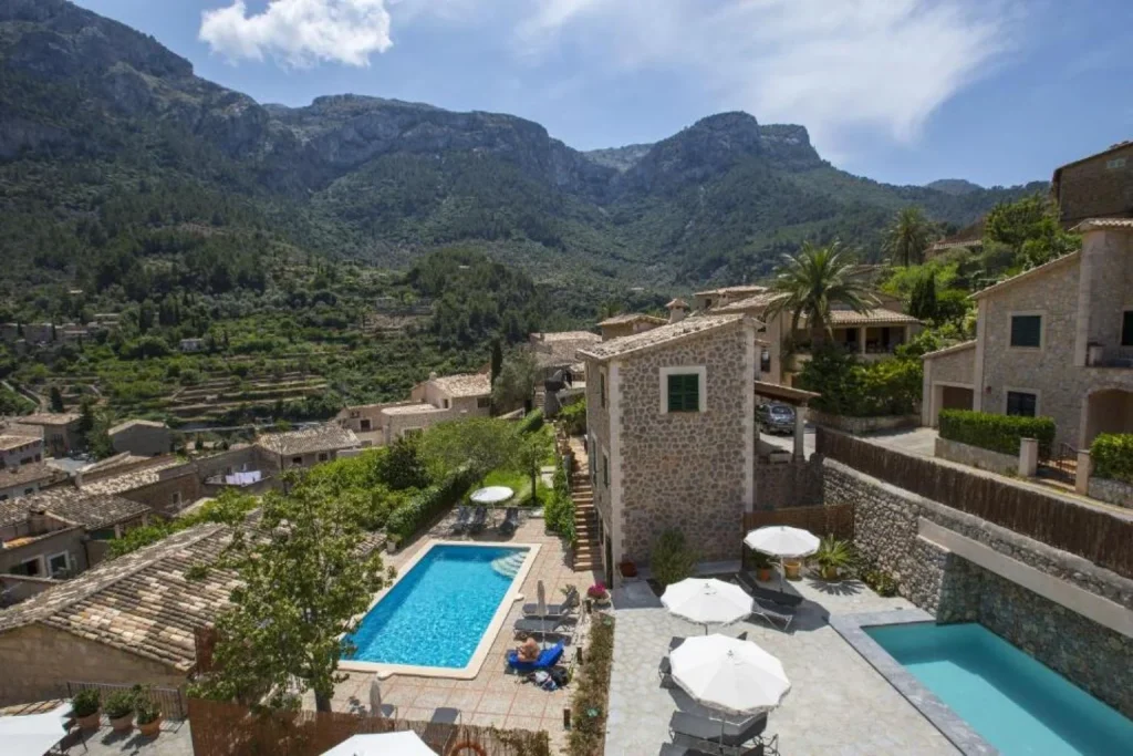Outdoor swimming pool with views of the Tramuntana mountains at Hotel y Apartamentos DES PUIG in Deià, Mallorca.