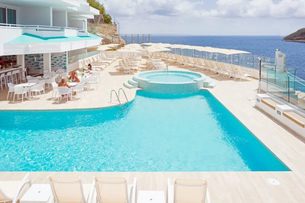 Oceanfront swimming pool with a hot tub, sun loungers, and sea views at HSM Sandalo Beach in Magaluf, Mallorca.