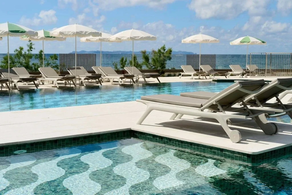 Seafront infinity pool with in-water loungers, sun loungers, parasols, spacious sun terrace, and panoramic Mediterranean views at Iberostar Selection Es Trenc in Mallorca