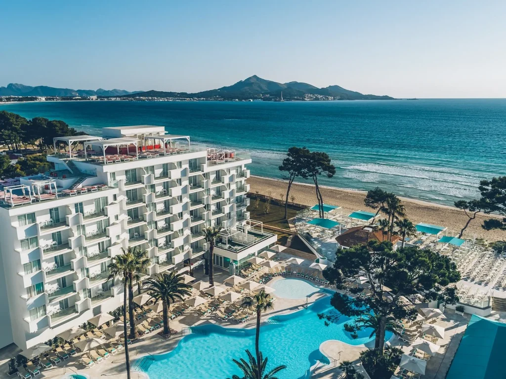 Beachfront hotel and pool overlooking the Mediterranean Sea at Iberostar Waves Alcudia Park in Playa de Muro, Mallorca.