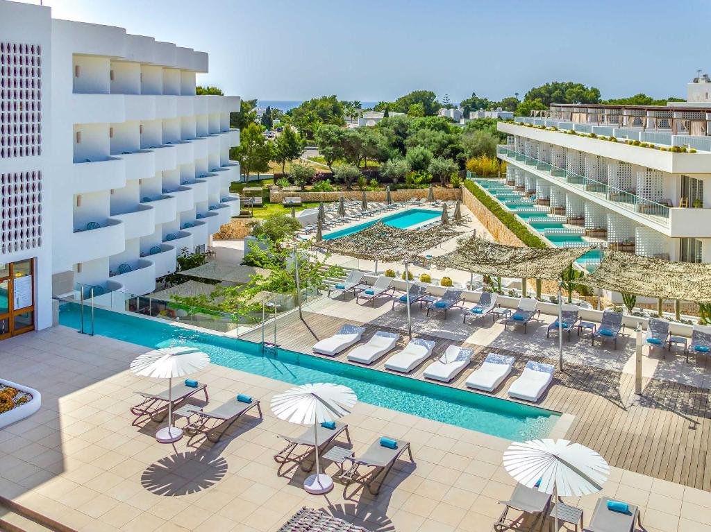 Outdoor pool, sun terrace, and hotel buildings at Inturotel Cala Esmeralda Beach Hotel & Spa - Adults Only in Cala d'Or, Mallorca.