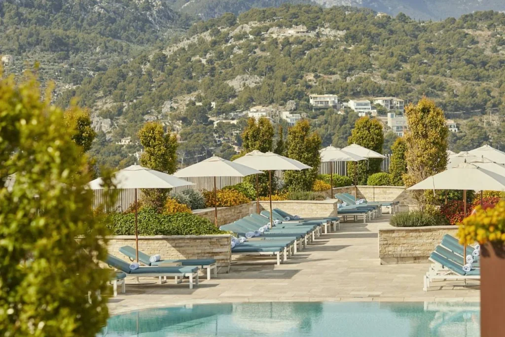 Infinity pool with sun loungers, parasols, and Tramuntana mountain views at Jumeirah Mallorca in Port de Sóller.