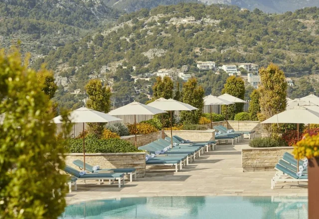 Infinity pool with sun loungers, parasols, and Tramuntana mountain views at Jumeirah Mallorca in Port de Sóller.
