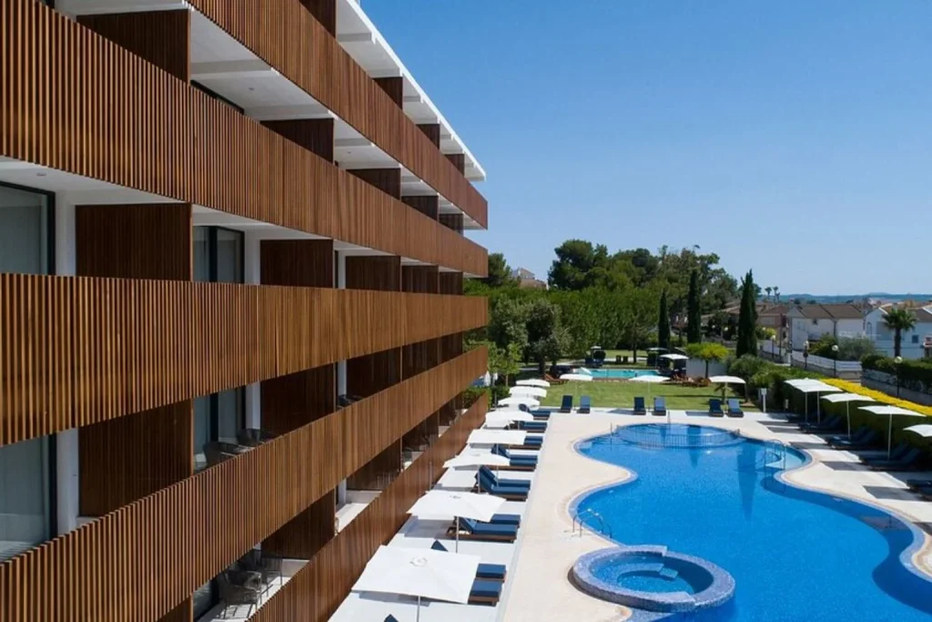 Elevated view of the outdoor swimming pool, sun loungers, and modern hotel balconies at Las Gaviotas Suites Hotel in Playa de Muro, Mallorca