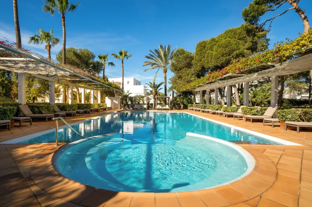 Outdoor swimming pool surrounded by gardens and palm trees at Meliá Cala d'Or Boutique Hotel in Cala d'Or, Mallorca.