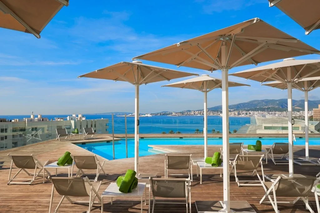 Rooftop infinity pool with sun loungers overlooking Palma Bay at Meliá Palma Bay in Palma de Mallorca.
