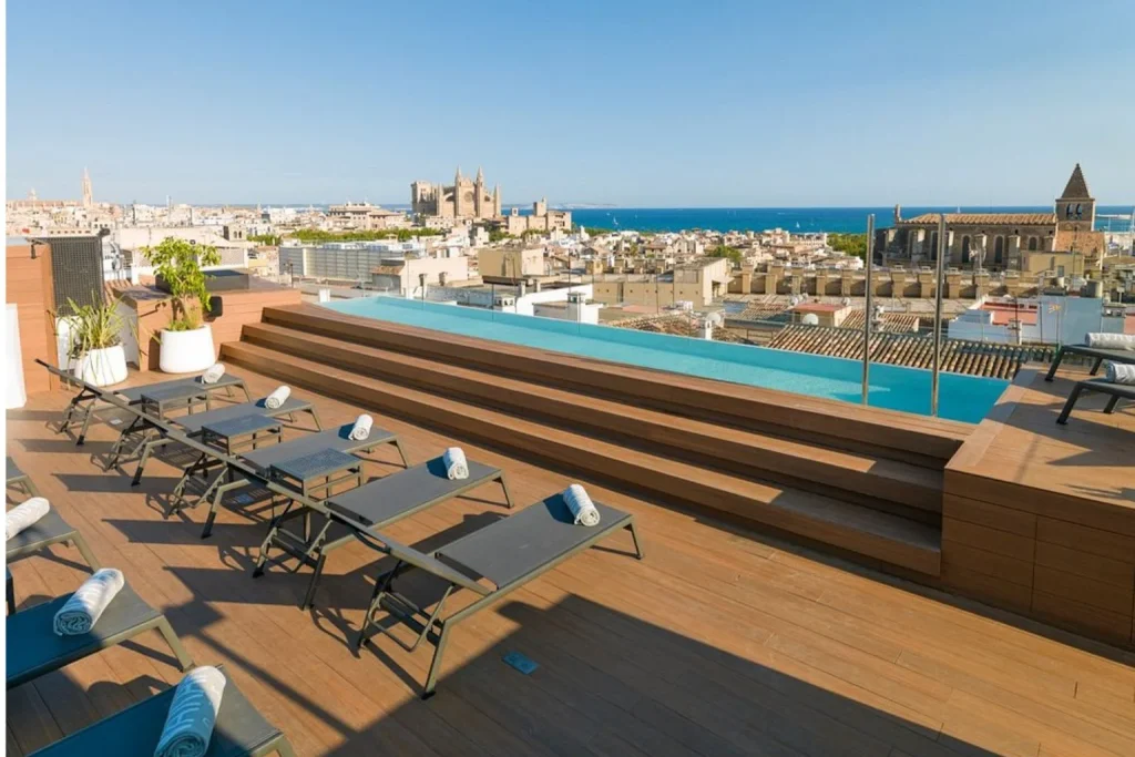 Rooftop infinity pool with sun loungers and panoramic city skyline views at Nakar Hotel in Palma de Mallorca