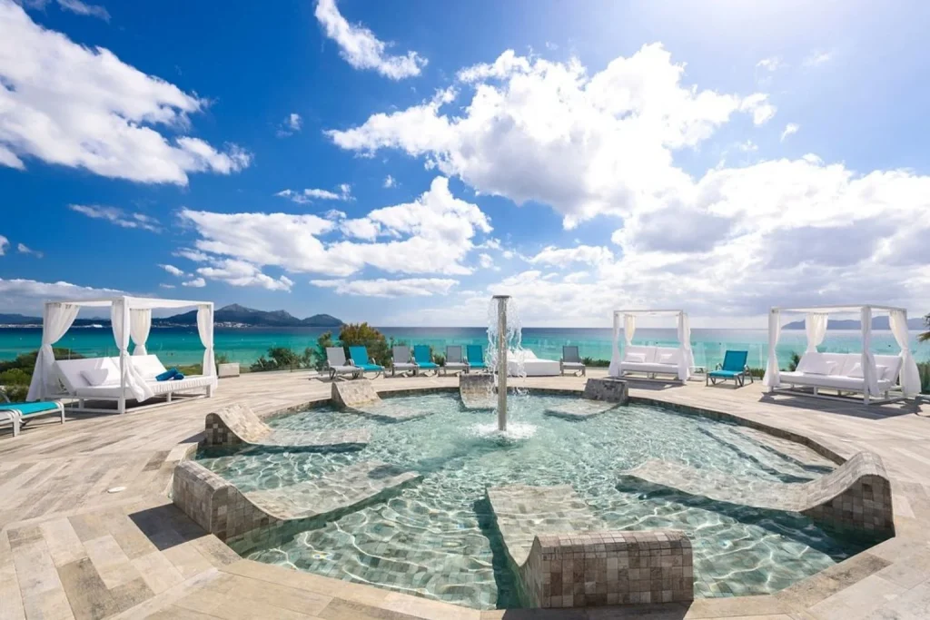 Seafront spa pool with hydrotherapy fountain, cabanas, and Mediterranean views at Playa Garden Selection Hotel & Spa in Playa de Muro, Mallorca.