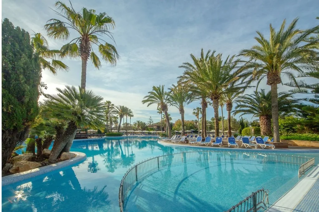 Lagoon-style swimming pool surrounded by palm trees at PortBlue Club Pollentia Resort & Spa in Pollença, Mallorca.