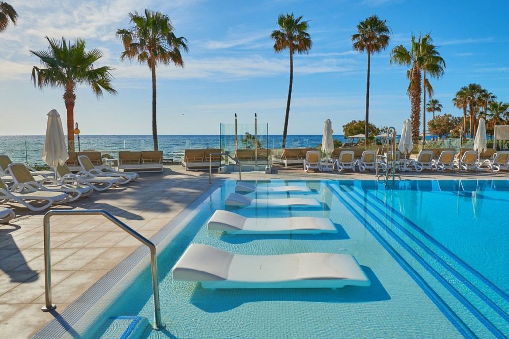 Seafront swimming pool with in-water loungers, sun terrace, and Mediterranean views at Protur Bonamar Hotel in Cala Bona, Mallorca
